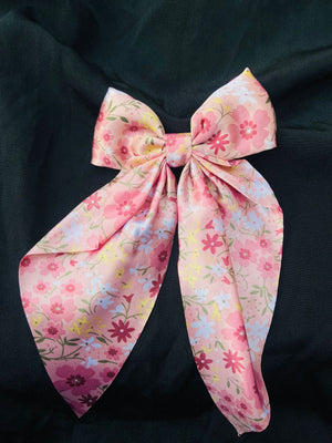 Elegant blush pink floral hair bow made of premium satin fabric, featuring a delicate wildflower meadow print for a romantic hairstyle."