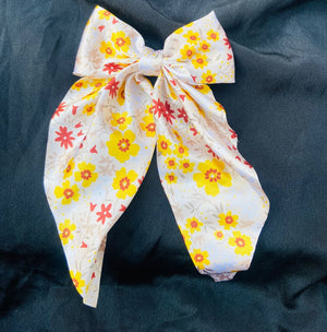 Bright white and yellow floral hair bow featuring a 'Sun-Kissed' daisy print on premium satin fabric, ideal for spring and summer hair styling."