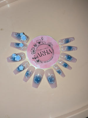 Nail art display with blue floral designs on clear nail sheets and a pink 'ARHA' logo.