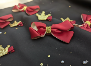 Red bows with gold accents and small crowns on a dark surface