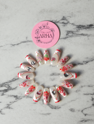 Decorative nail art designs arranged in a circle on a marble surface with a pink 'ARHA' logo.