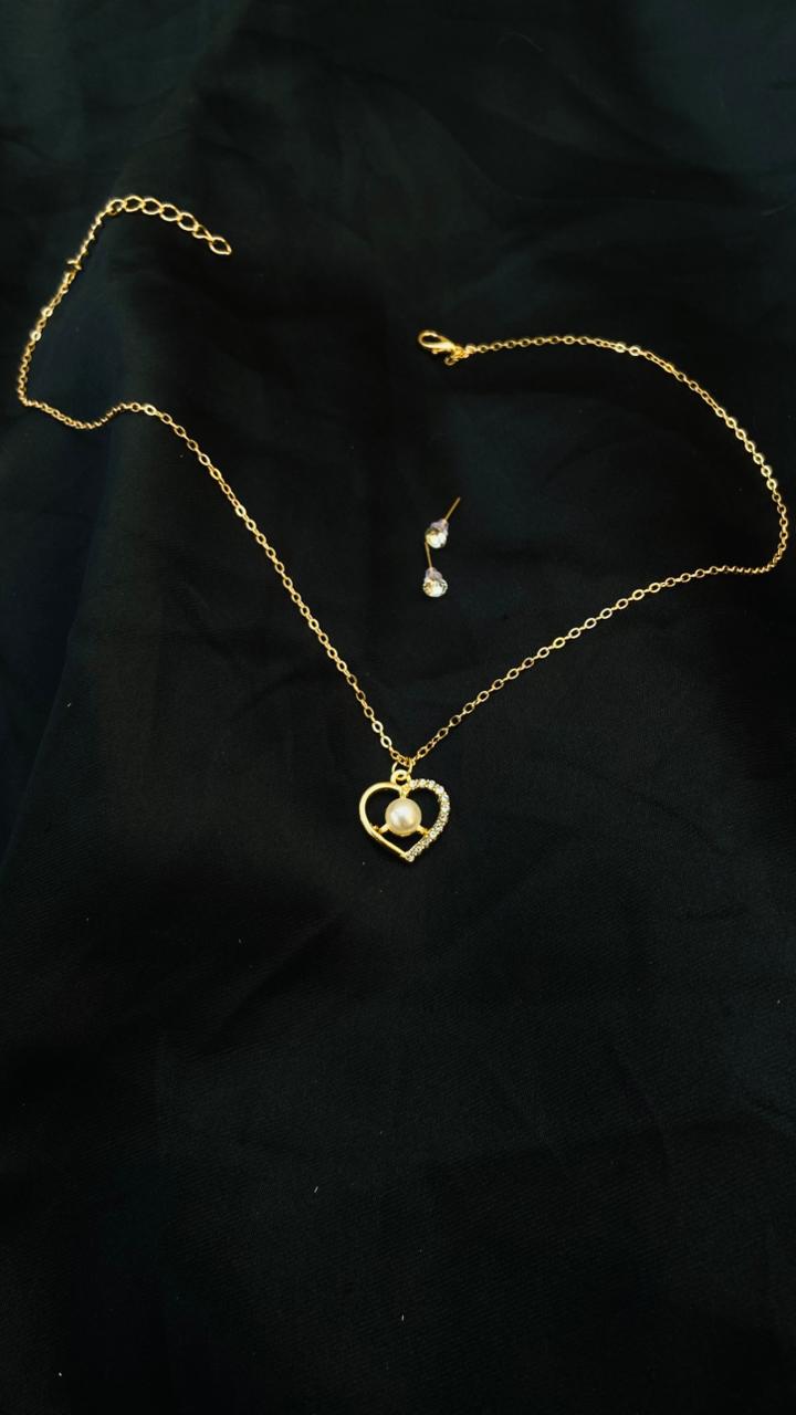Gold necklace with a heart-shaped pendant on a black background