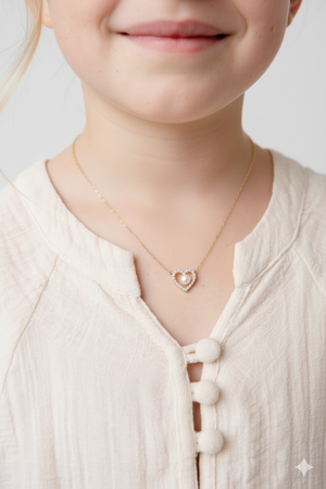 Child wearing a necklace with a heart-shaped pendant on a plain background