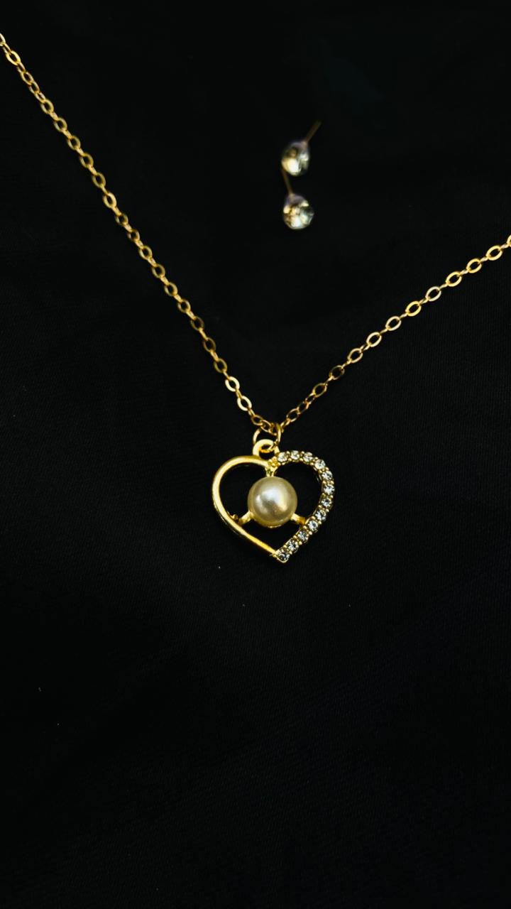 Gold necklace with a heart-shaped pendant featuring a pearl on a black background