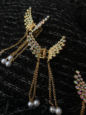 Gold butterfly earrings with pearl accents on a black textured background