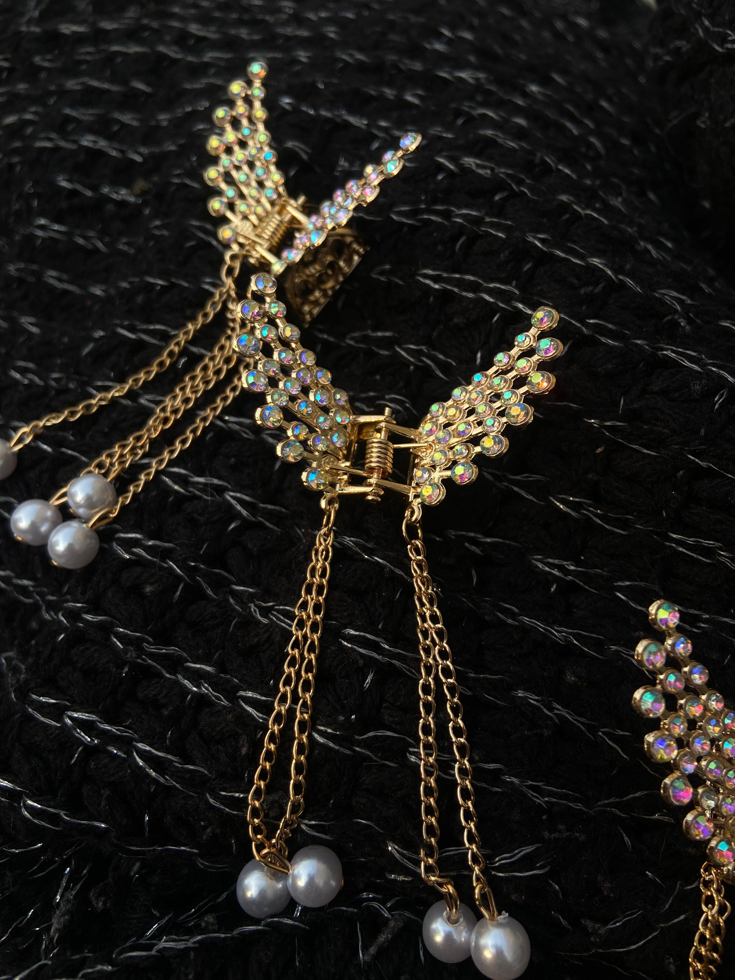 Gold butterfly earrings with pearl accents on a black textured background