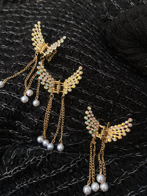 Gold butterfly earrings with pearl accents on a textured black surface
