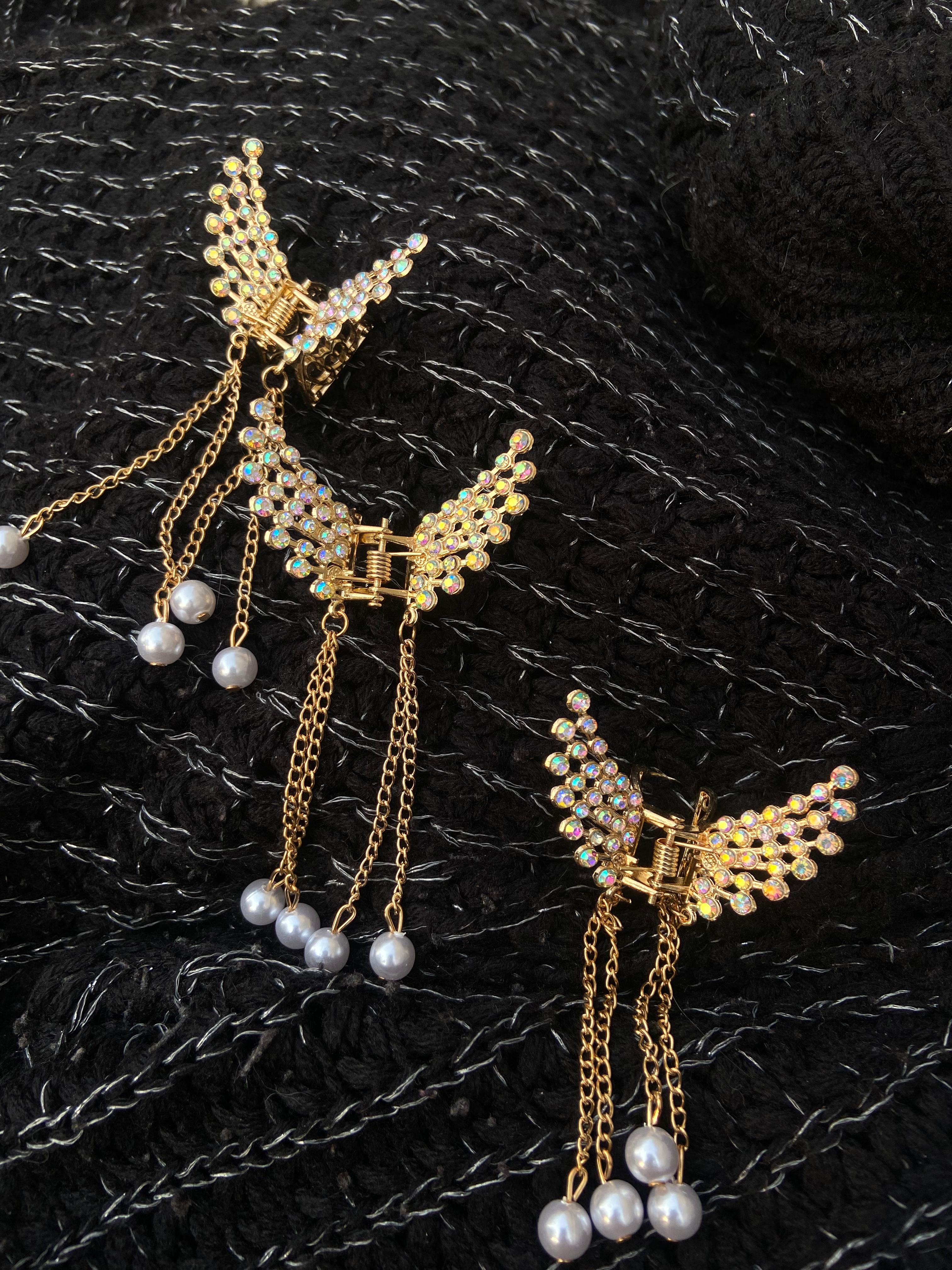 Gold butterfly earrings with pearl accents on a textured black surface