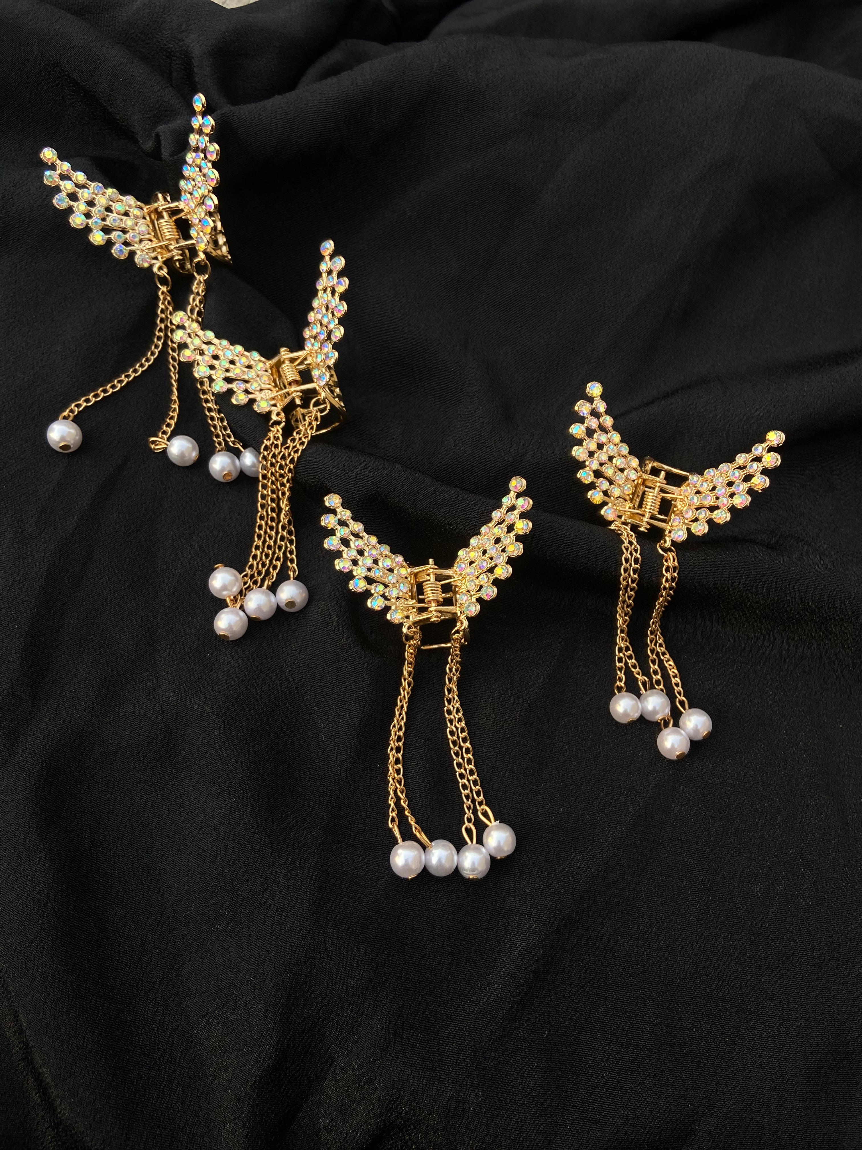 Gold bird-shaped earrings with pearl accents on a black fabric background